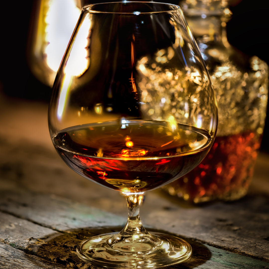 Verre de rhum avec sa carafe posé sur une table en vieux bois.