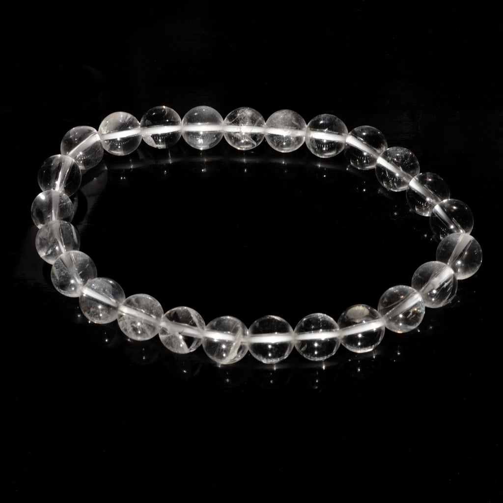 Bracelet boule en cristal de roche du Brésil sur fond noir éclairé par la lumière du soleil.
