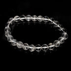 Bracelet boule en cristal de roche du Brésil sur fond noir éclairé par la lumière du soleil.