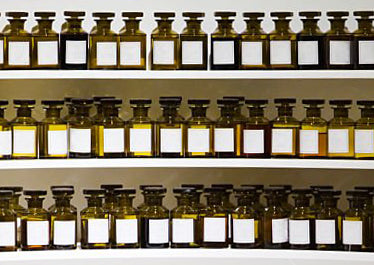 De nombreux flacons de parfum couleur ambre posés sur un orgue à parfum à trois étages.