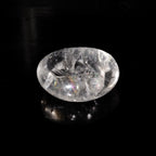 Photo d'une pierre roulée en cristal de roche de qualité AA provenant du Brésil sur fond noir éclairé par la lumière du soleil. Le soleil donne à la pierre de cristal de roche des éclats aux couleurs de l'arc-en-ciel.
