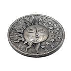 Ce porte-encens décoratif rond en aluminium recyclé, représente un soleil, une lune et des étoiles, symboliques d'une célébration céleste de la spiritualité.